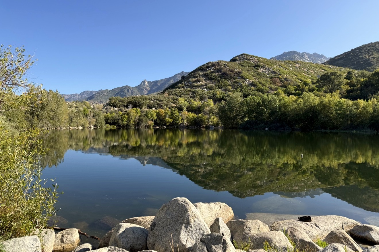 A still alpine lake reflecting pines and snow-streaked peaks